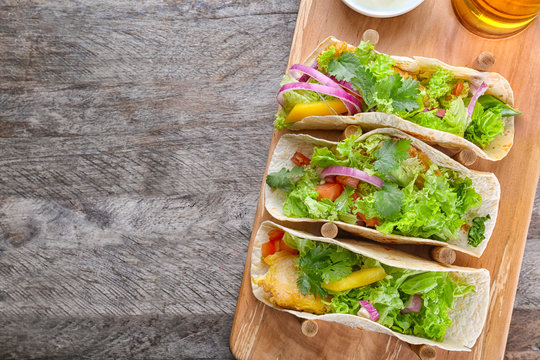 Wooden holder with yummy fish tacos on kitchen table