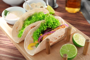 Holder with delicious fish tacos on wooden table