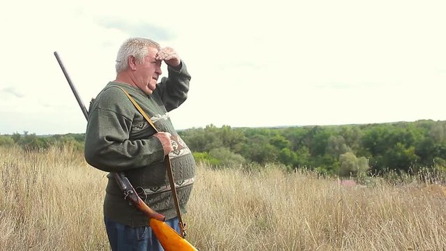 Hunter aiming the hunt during the hunting season. Hunter waiting silently for the hunt during the hunting season. Hunter in camouflage clothes with hunting rifle.
