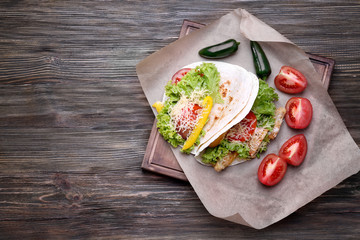 Wooden board with delicious fish tacos on kitchen table