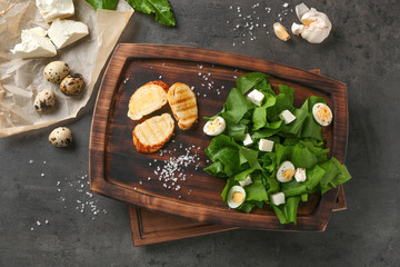 Salad with quail eggs and spinach on wooden board