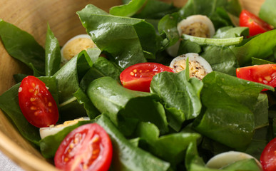 Salad with quail eggs and spinach in bowl on table