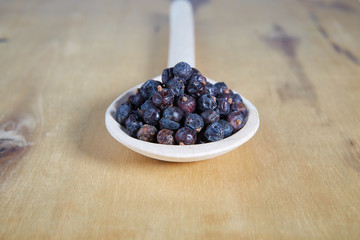 Juniper seeds on a wooden spoon. 
