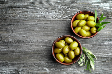 Bowls with tasty olives on wooden background