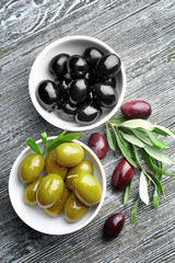 Bowls with tasty olives on wooden background