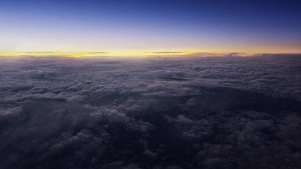 Flying over the evening clouds with the late sun. Flight through moving cloudscape with beautiful sun rays. Traveling by air through an airplane window. Perfect for posters, background