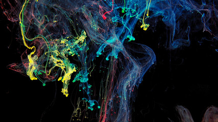 Colorful rainbow paint drops from mixing in water. Ink swirling underwater. Cloud of ink isolated on black background. Colored abstract smoke explosion effect. Close up view