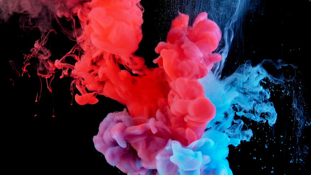 Real shot color paint drops in water. Ink swirling underwater. Cloud of ink collision isolated on black background. Colorful abstract smoke explosion. Close up view