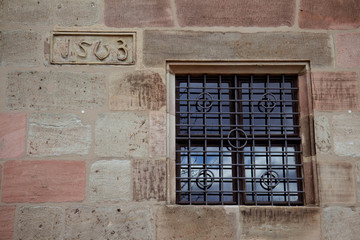 Fototapeta na wymiar a building wall with a window and a date of construction cared in stone (1503); Nuremberg, Germany