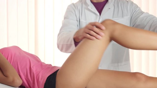 Doctor traumatologist check female patient's knee joint