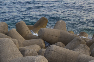 Fototapeta na wymiar Frangiflutti artificiali di pietro proteggono il porto dal mare aperto. L'ora del tramonto dona le tonalità calde al panorama.