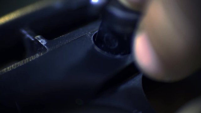 Macro shooting as a man's hands insert a fuse into the disassembled gun
