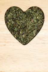Dried nettle leaves heart shaped on wooden surface