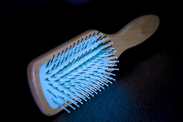 Blue tip hair comb with wooden handle isolated on black background.