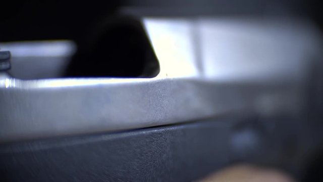 Men's hands pull back the bolt of the pistol and from there drops a bullet, macro shooting