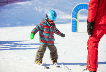 Young skier and ski instructor on slope in beginners' area