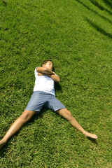 A boy is happy relaxing on green juicy grass in a park