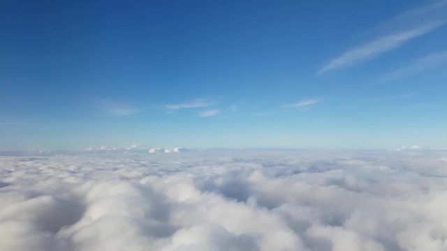 Stunning footage of aerial view above clouds from airplane window with blue sky. Shot in 4k resolution