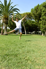 A boy is happy jumping on green juicy grass in a park