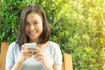 Asian woman hand using mobile phone in garden with copy space