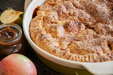 Traditional American apple pie in a ceramic form and ingredients on a wooden table. Close up and overhead view.
