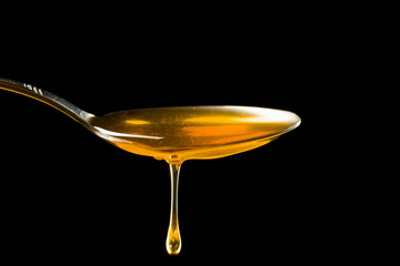 Spoonful of honey on the black background