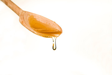 Spoonful of honey on the wooden spoon on the white background