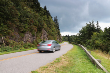 Blue Ridge Parkway scenic view. Summer landscape with cloudy sky over the road with car in motion...