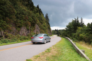 Blue Ridge Parkway scenic view. Summer landscape with cloudy sky over the road with car in motion passing through Great Smoky Mountains scenic highway Blue Ridge Parkway at North Carolina, USA.