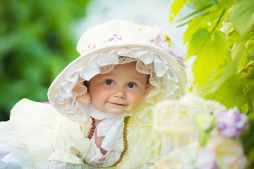 Beautiful little girl in a white dress and hat in a spring garden.