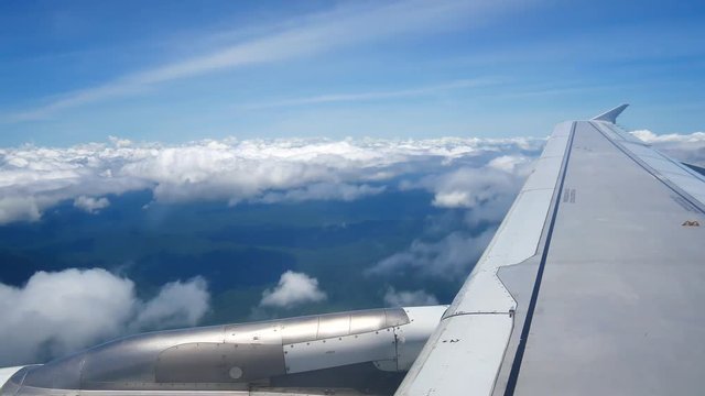 A view from the airplane window over the wings and engines. The planes are flying above the clouds and sky in transportation or travel concept.