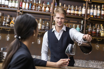 Bartender serving Wine to Customer at counter, Bartender enjoy to serving Wine for Customer, People Lifestyle Concept.