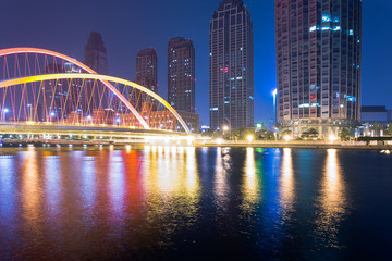 Tianjin Hai river waterfront downtown skyline with illuminated Dagu bridge,China.