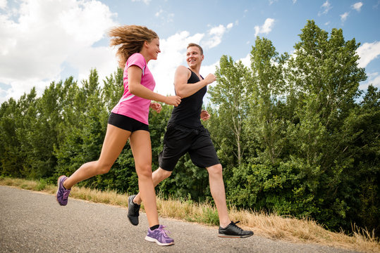 Healthy smiling fitness couple running outdoors