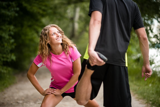 Couple relaxing their leg muscles before jogging