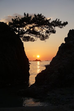 Brilliant Sunrise behind rocks on the seashore.