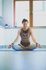 Fototapeta na wymiar Young woman doing yoga at home in the lotus position. Yoga. Woman. Lifestyle