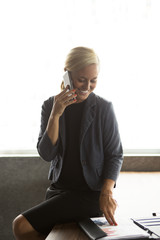 Happy businesswoman talking to colleague on phone