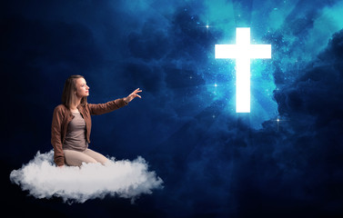 Woman sitting on a cloud looking at a cross