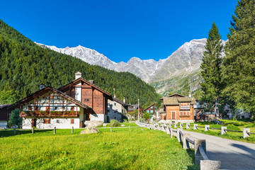 Picturesque and characteristic alpine village, Italy. Macugnaga (Staffa), little touristic village with wooden and stone houses at the foot of the east wall of Monte Rosa, on a beautiful summer day - obrazy, fototapety, plakaty