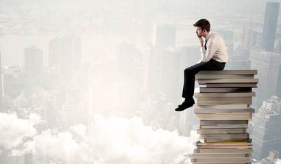 Student in city sitting on stack of books
