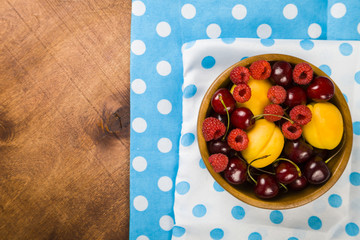 Ripe berries in a plate on a wooden table.