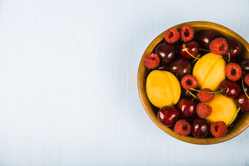 Ripe berries in a plate on a wooden table.