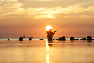 Fototapeta premium Angler bei Sonnenaufgang am Meer