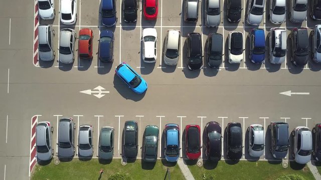 AERIAL TOP DOWN: Flying above female bad driver incapable to park a car on parking space in crowded parking lot. Woman having problems, unable to park a car in parking spot. Parking fail on parkspace