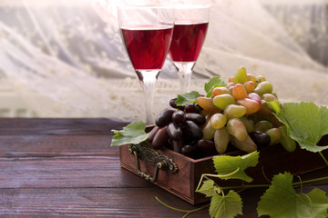 Sweet grape branches and two wine glasses, ripe fruits with green leaves  in wooden box