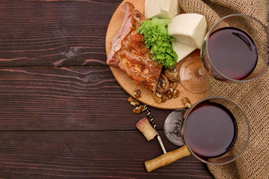 Meat, cheese and wine glasses on a table with linen cloth on background of wooden planks