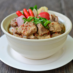 Top view of Thai spicy soup with pork ribs. Decorated with vegetable and herb on wooden texture of dining table. (Thai Traditional Foods)