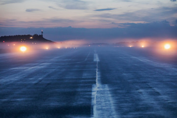 Lege landingsbaan op luchthaven tijdens een mistige avond