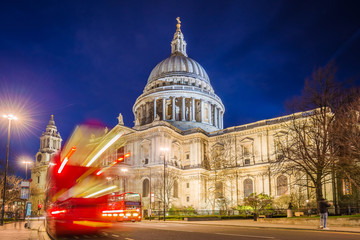 London, England - The Saint Paul's Cathedral with famous old red double decker buses on the move at night